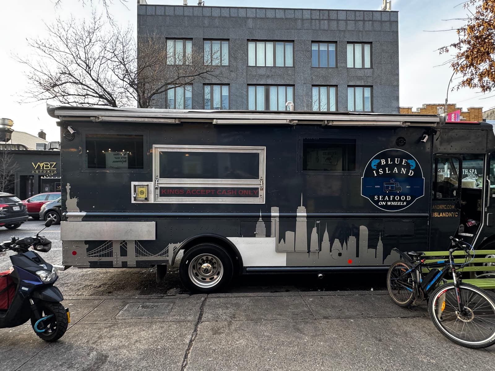 Dark grey Blue Island Seafood food truck with a Statue of Liberty and skyline illustration, serving window, parked on a Brooklyn street