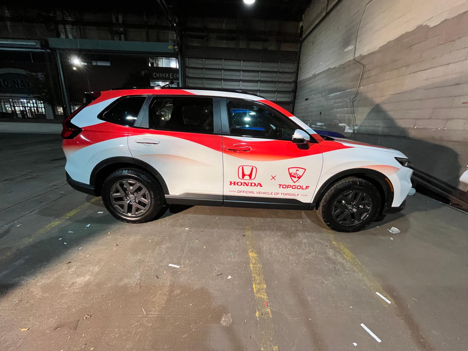 White Honda CR-V with red and blue stars-and-stripes graphics and TopGolf Cup 2025 and Honda logos, in the wrap shop