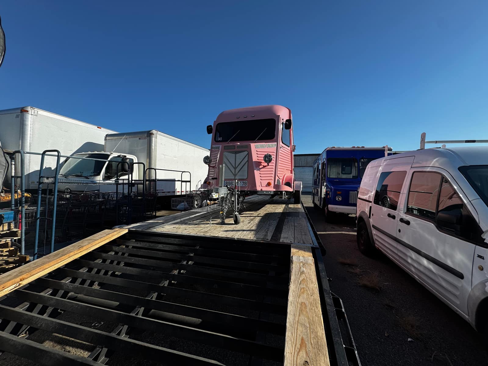 Pink Godiva promo truck loaded on a flatbed trailer in a truck yard, daylight