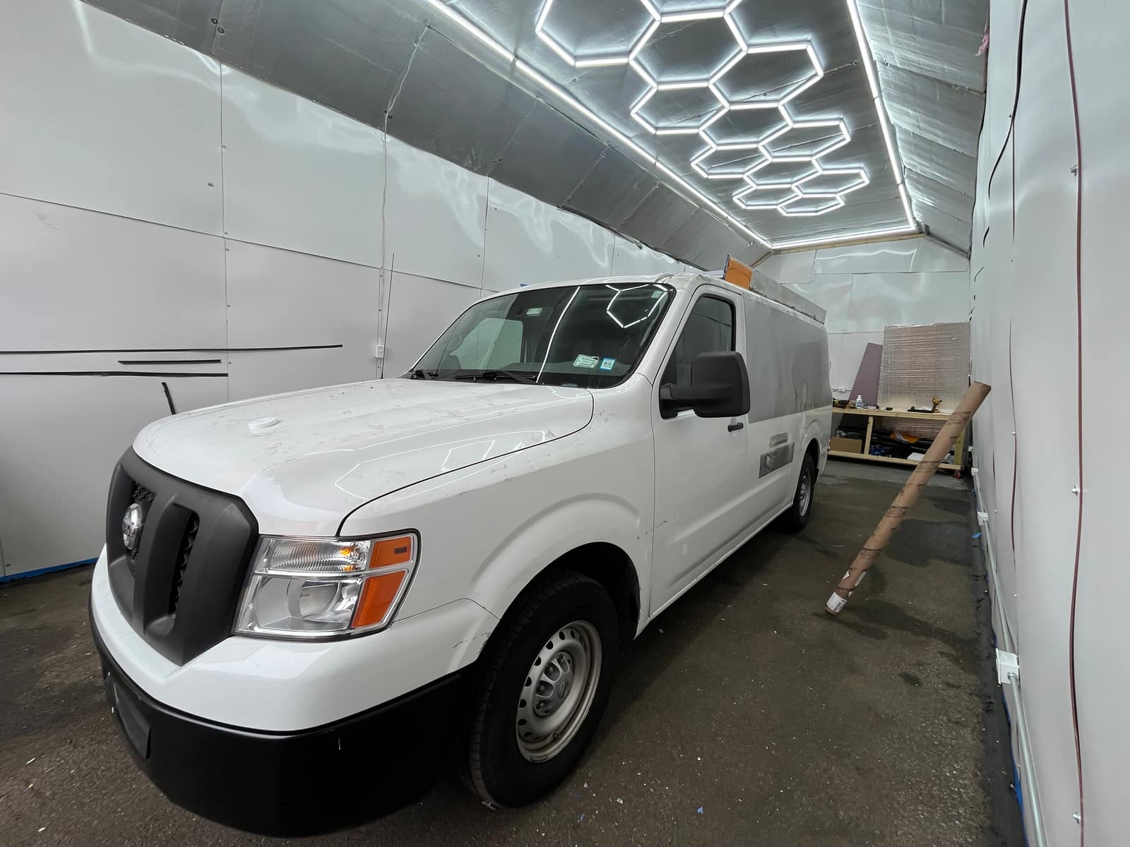 Unwrapped white Nissan NV cargo van in the shop before wrapping