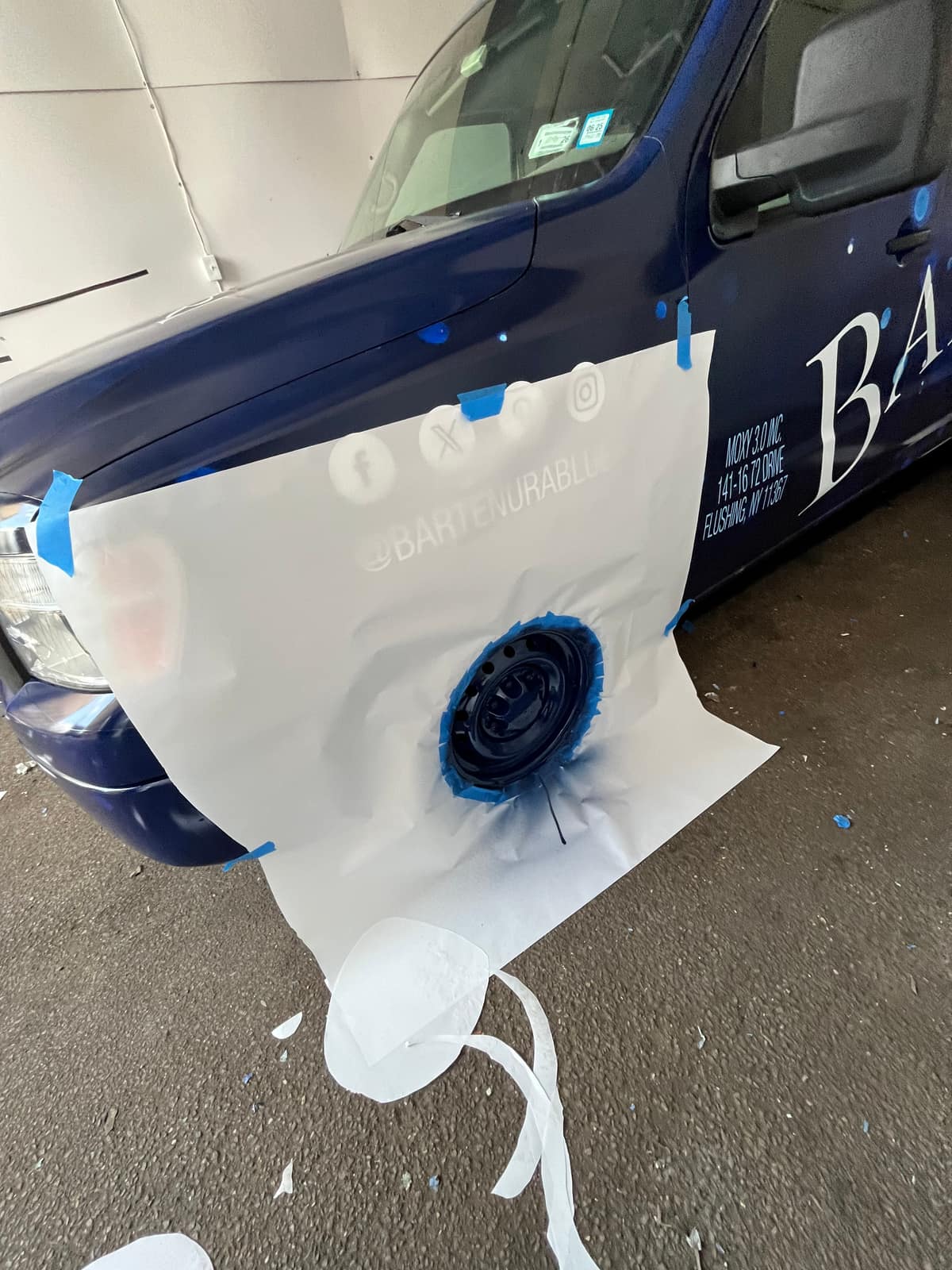 Close-up of an installer trimming film at a wheel arch during a full van wrap