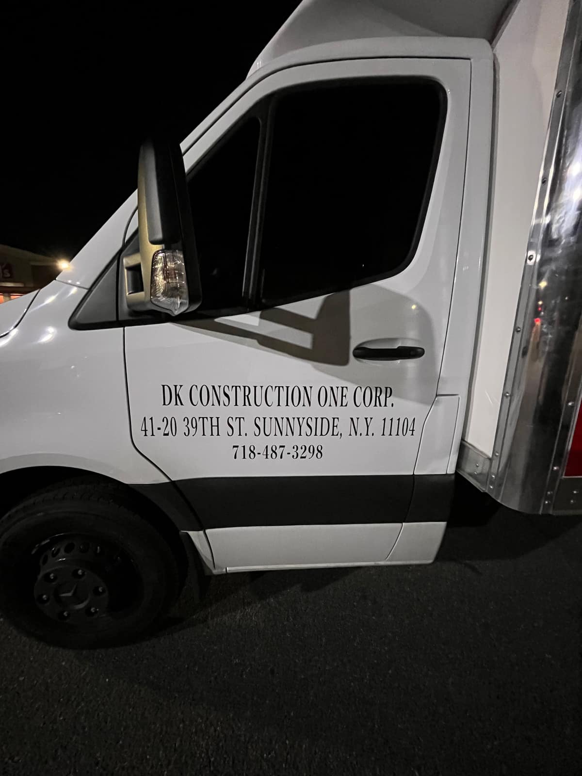 Close-up of cut vinyl lettering on the lower door of a white Sprinter van
