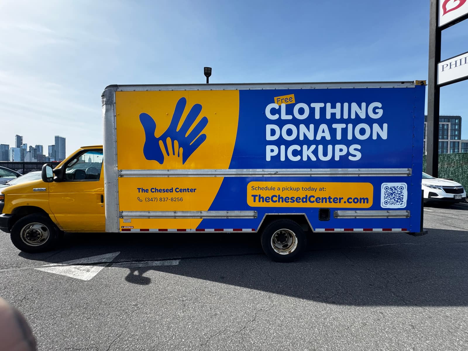 The Chesed Center box truck with a printed clothing donation wrap on a flat box side