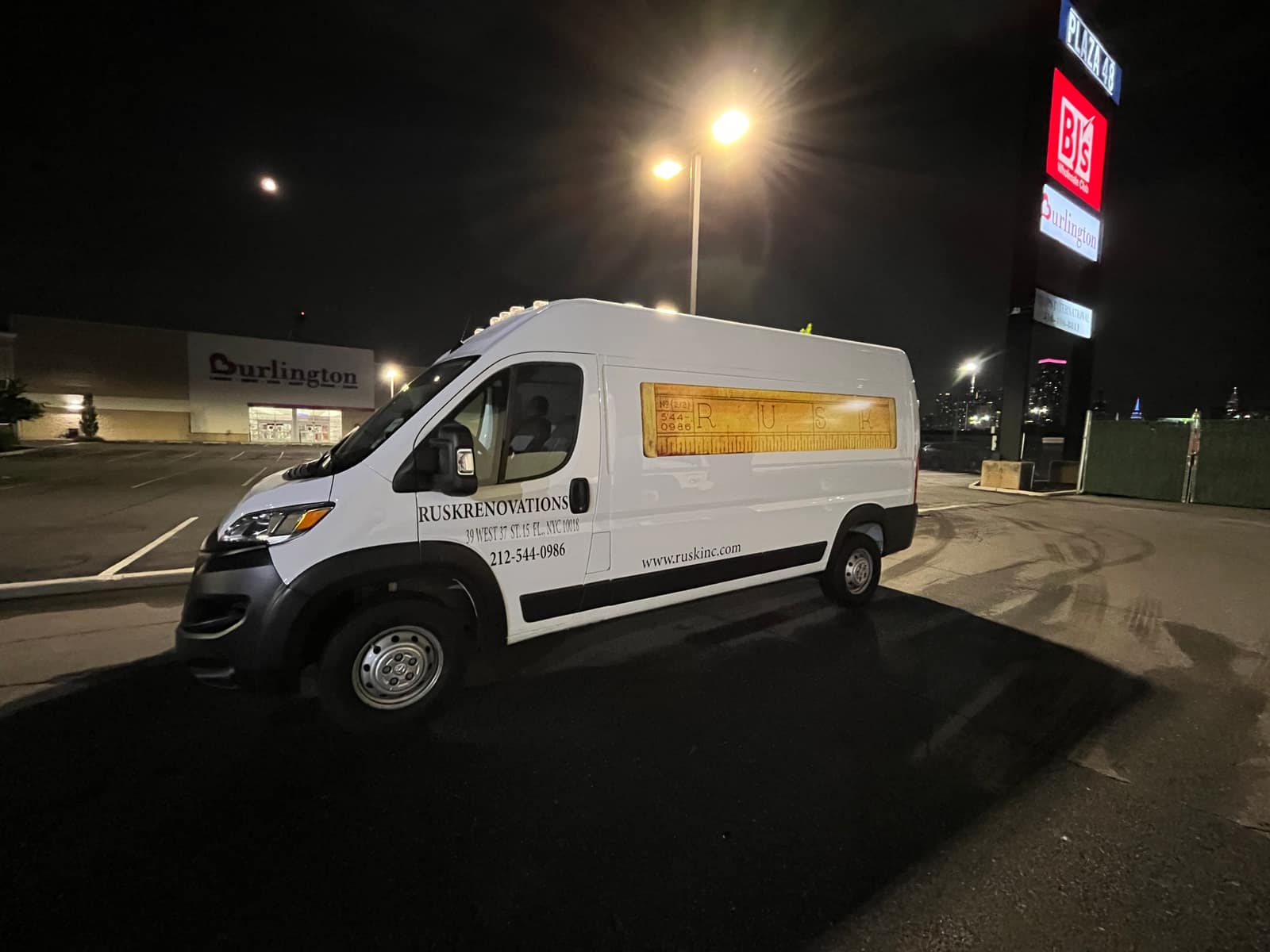 White Ram ProMaster for Rusk Renovations at night with a printed side panel and cut vinyl lettering