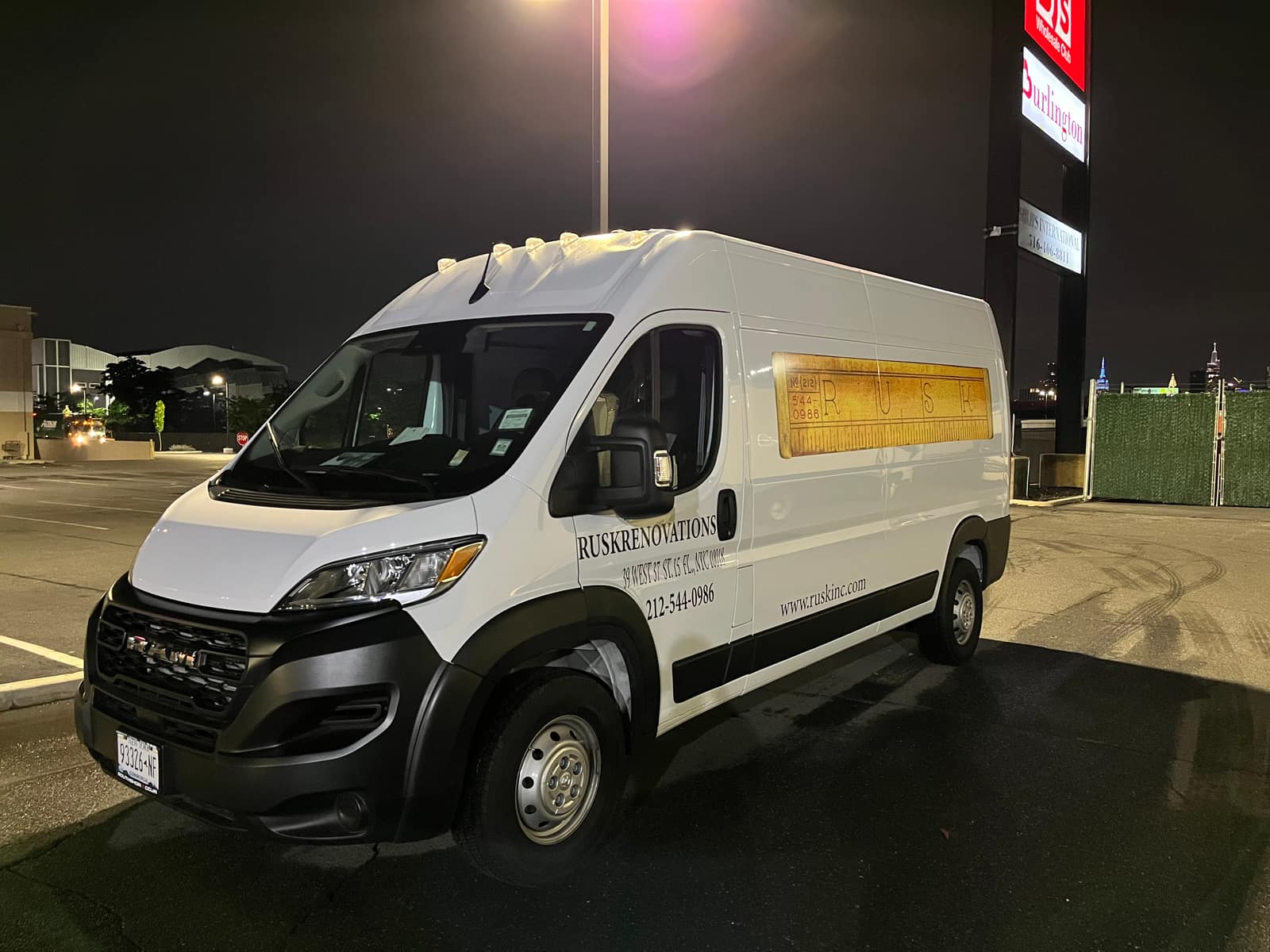 White Ram ProMaster van for Rusk Renovations with a printed side panel and West 37th Street lettering, photographed at night in a parking lot