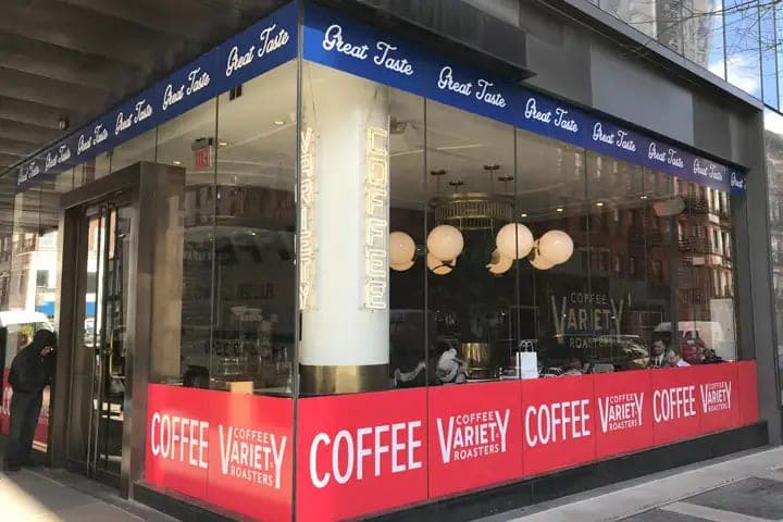 Cafe storefront with a red Coffee and Variety window band and Great Taste lettering on the awning