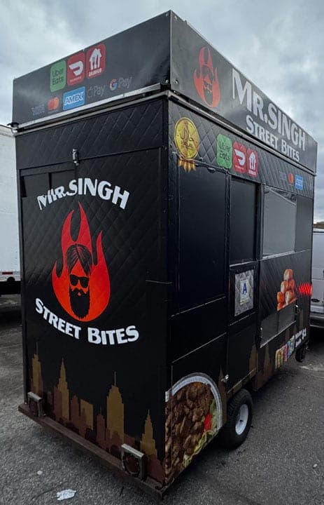 Mr. Singh Street Bites black food cart with red flame logo, skyline band and printed food and chip panels, side view