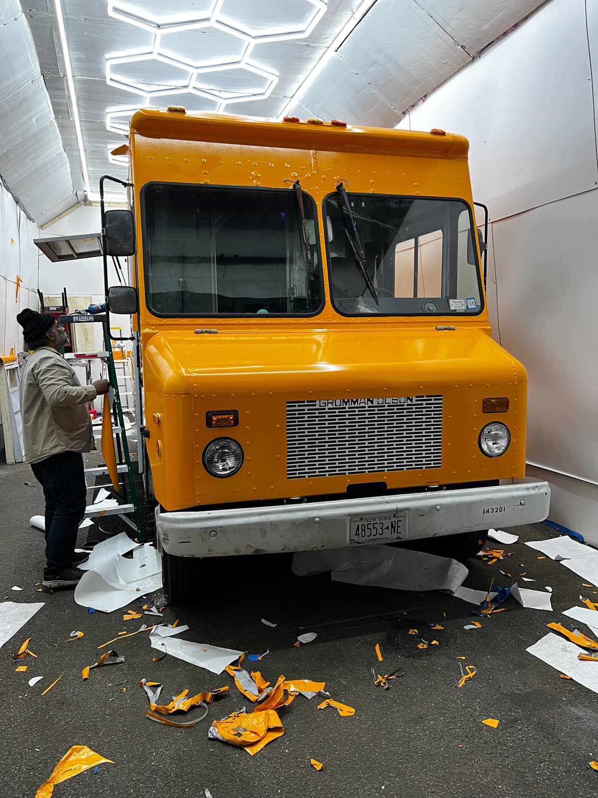Installer wrapping an orange step van for a brand activation