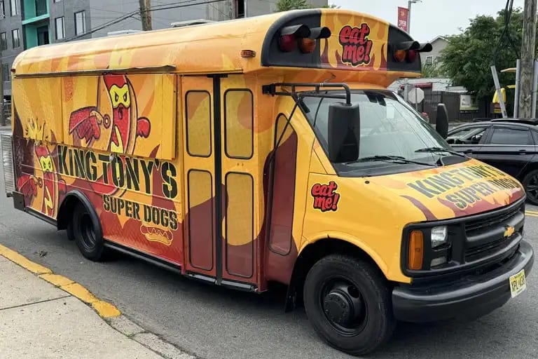 Yellow school-bus-style King Tony's Super Dogs hot dog truck with orange flame graphics, side view