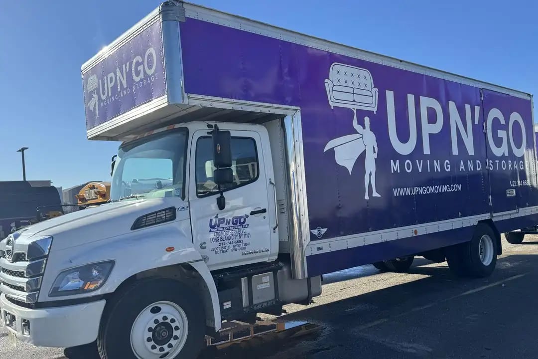 Purple Up N' Go Moving and Storage Hino box truck with a printed box wrap and cab lettering, side view